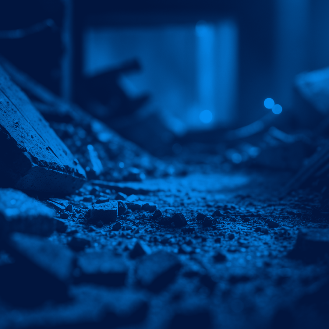 Close-up view of rubble and broken concrete pieces on the ground, shown in a blue colour tone.